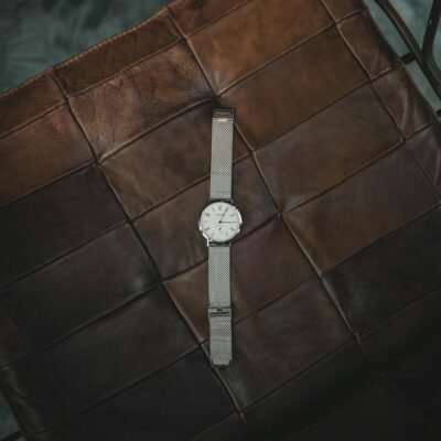 Elegant silver wristwatch resting on a brown leather seat, showcasing elegance and style.