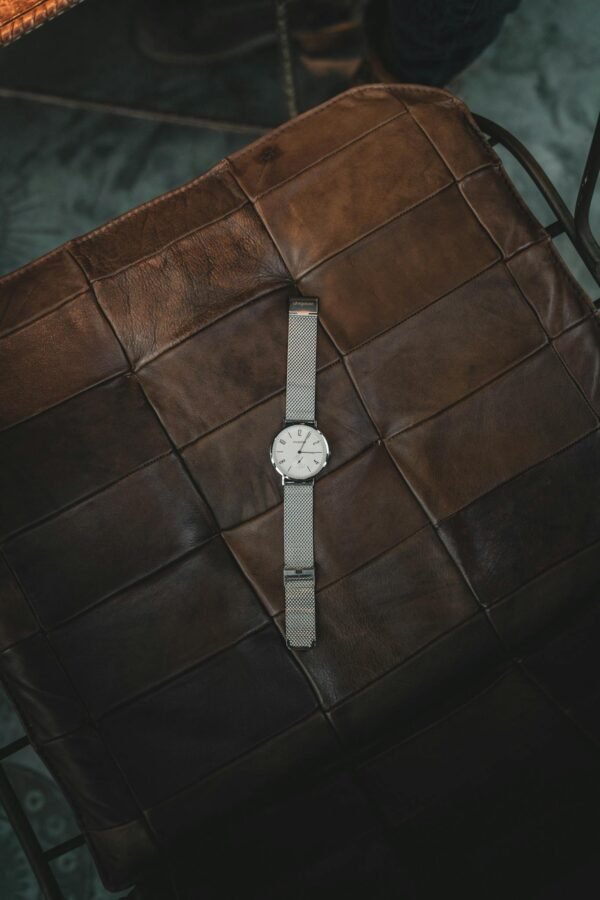 Elegant silver wristwatch resting on a brown leather seat, showcasing elegance and style.