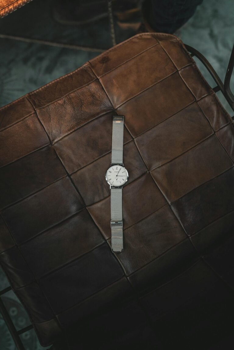 Elegant silver wristwatch resting on a brown leather seat, showcasing elegance and style.