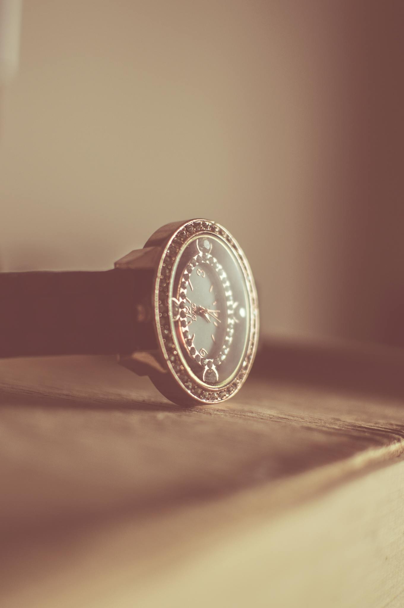 Elegant vintage wristwatch with ornate design, resting gently on a wooden surface, captured in soft focus.